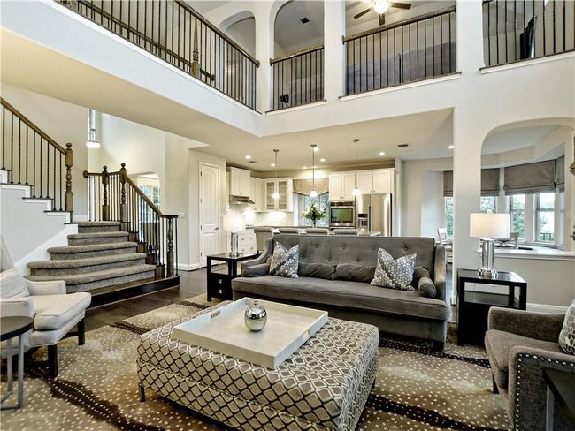 Living room with stairway, ceiling fan, a towering ceiling, and dark wood-style flooring | Image 12
