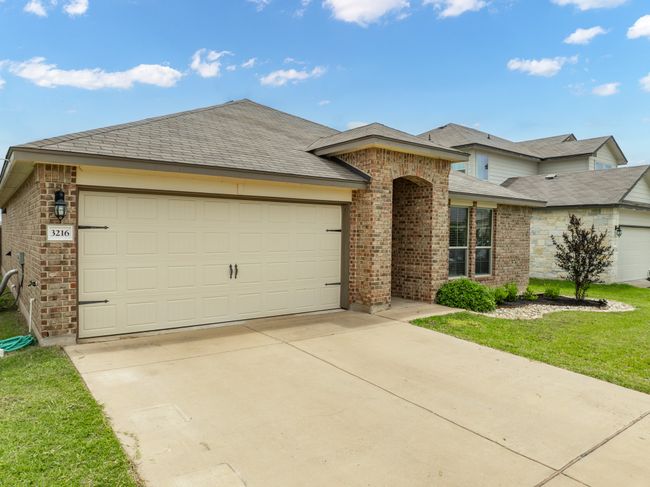 View of front of home with brick siding, concrete driveway, a garage, a front lawn, and roof with shingles | Image 4