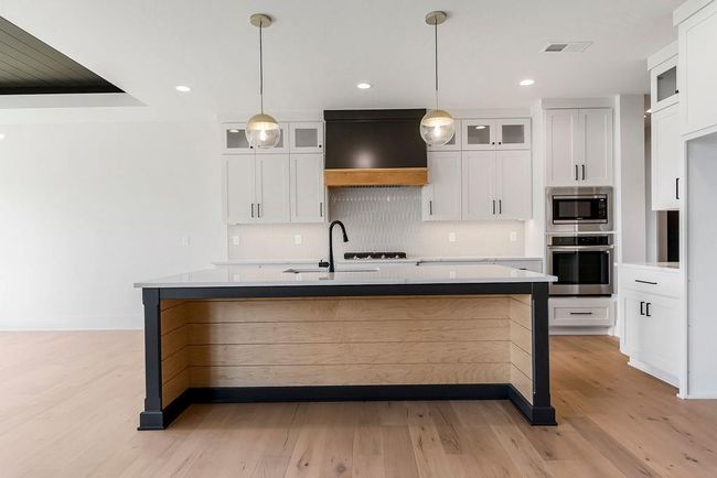Kitchen featuring appliances with stainless steel finishes, decorative backsplash, light wood finished floors, an island with sink, and recessed lighting | Image 7