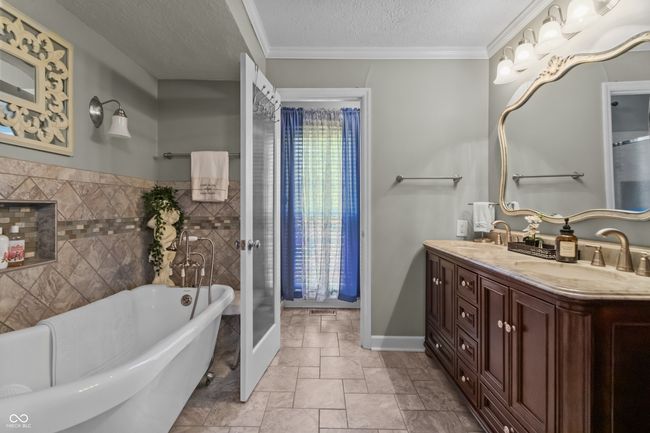 bathroom featuring double vanity, a soaking tub, and a stand up shower that isn't pictured. | Image 20