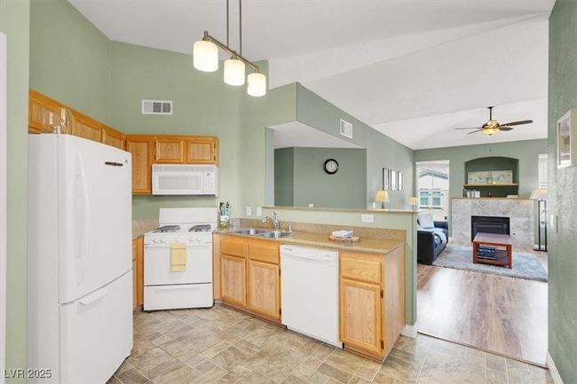 Kitchen featuring visible vents, white appliances, a peninsula, and a sink | Image 16