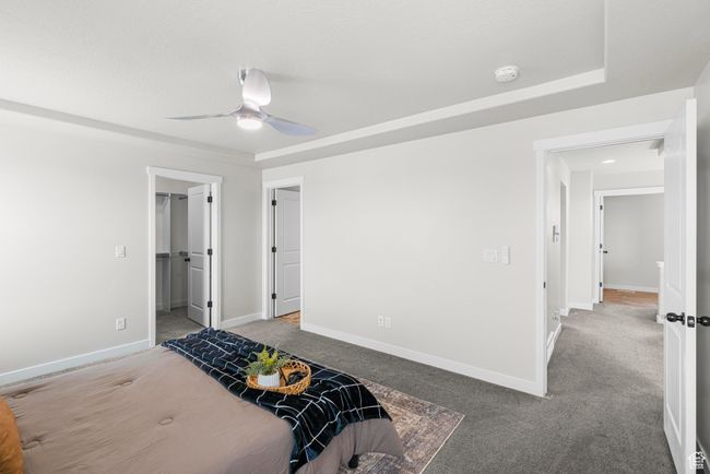 Bedroom with baseboards, a ceiling fan, a walk in closet, and light colored carpet | Image 20
