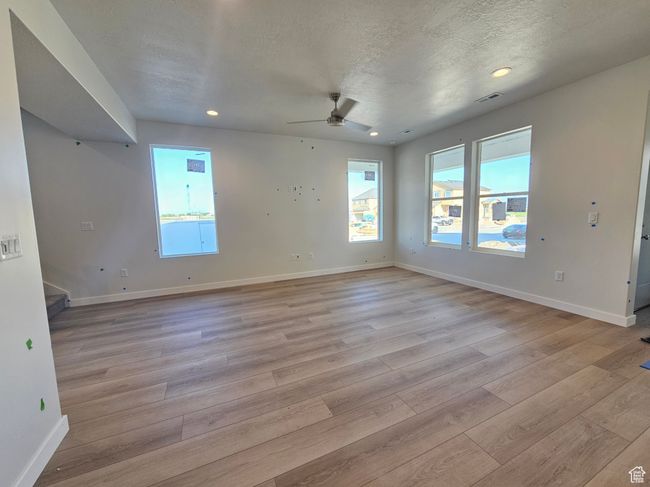 Empty room with light wood-style floors, stairs, a ceiling fan, recessed lighting, and a textured ceiling | Image 13