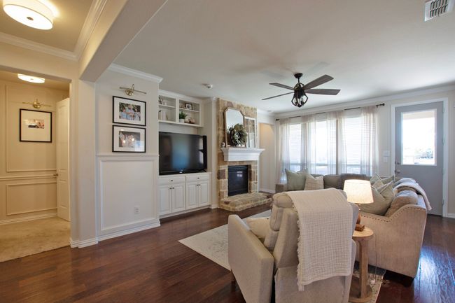 Living room featuring dark wood finished floors, built in shelves, a large fireplace, a ceiling fan, and visible vents | Image 15