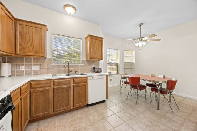 Kitchen featuring white dishwasher, decorative backsplash, stove, and brown cabinetry | Image 12