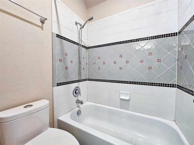 Bathroom featuring toilet, a textured wall, and shower / bathtub combination | Image 24