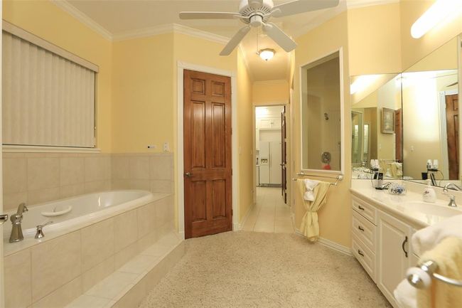 This primary bathroom has a soaking garden tub, walk in shower, marble vanity, and his and hers walk in closets. | Image 34