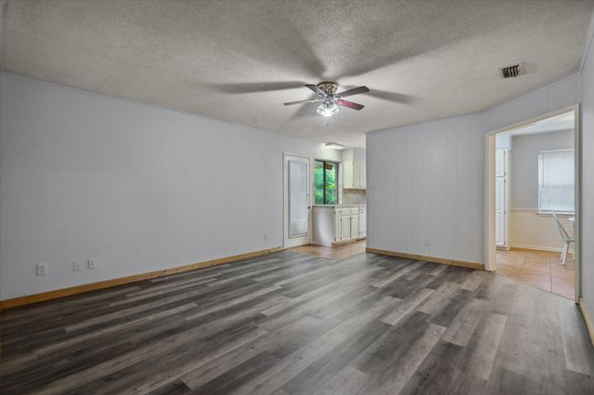 Empty room featuring a ceiling fan, wood finished floors, and a textured ceiling | Image 5