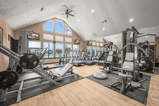 This is a spacious Fitness Center, with high ceilings, large arched windows providing natural light, and a variety of fitness equipment, perfect for a fitness enthusiast looking for a private workout space. | Image 32