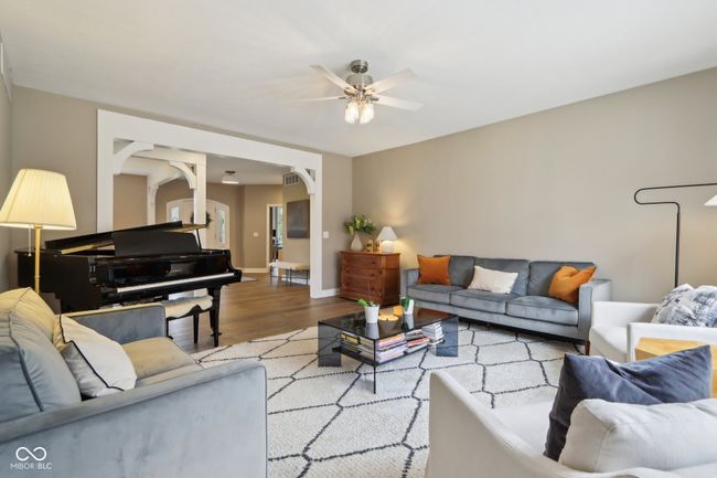 living area with a ceiling fan, arched walkways, baseboards, and light wood finished floors | Image 12