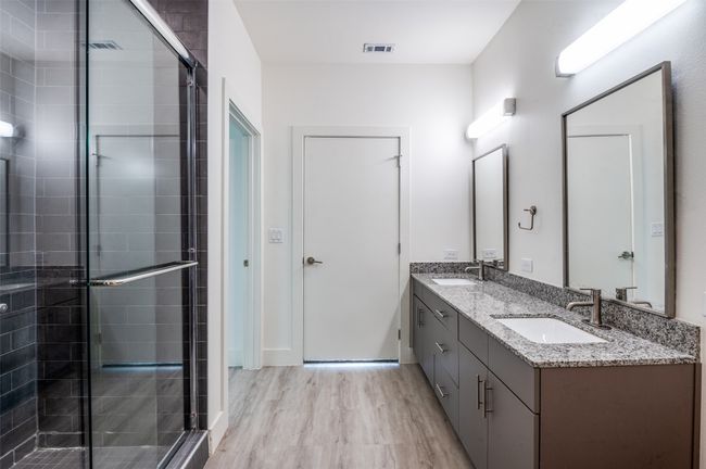 Full bath featuring double vanity, a stall shower, and wood finished floors | Image 20