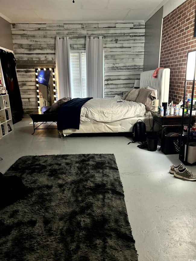 Bedroom featuring concrete floors, crown molding, and wooden walls | Image 14