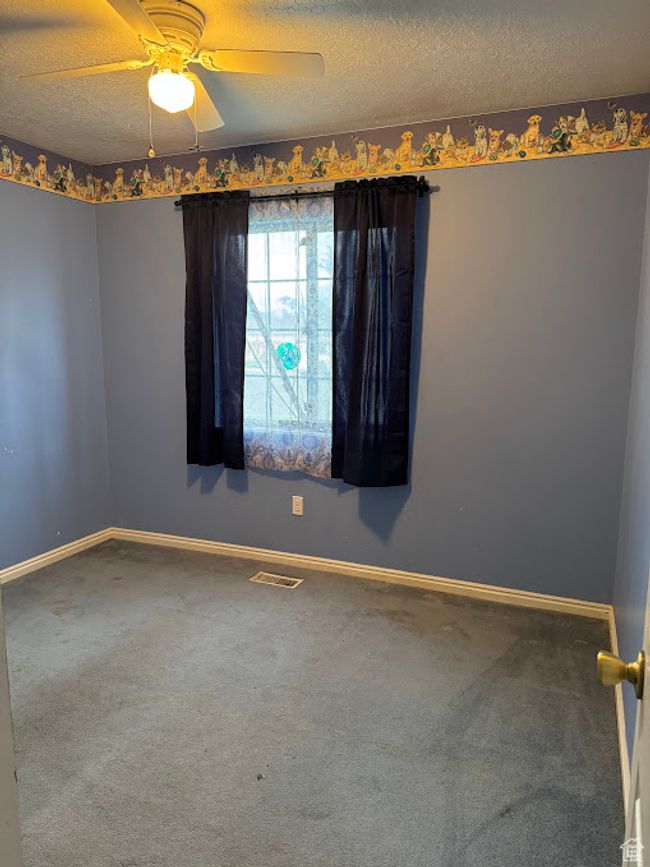 Empty room with carpet floors, baseboards, ceiling fan, and a textured ceiling | Image 16