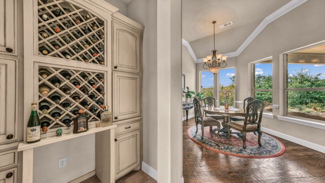 Wine cellar featuring a chandelier, visible vents, crown molding, baseboards, and lofted ceiling | Image 18