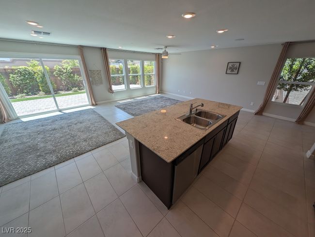 Kitchen featuring light tile patterned floors, open floor plan, ceiling fan, a center island with sink, and recessed lighting | Image 11