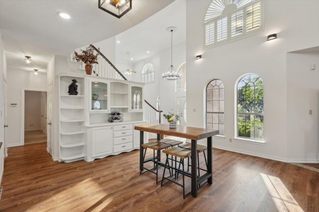 Dining room featuring a high ceiling, a chandelier, wood finished floors, recessed lighting, and stairway | Image 13