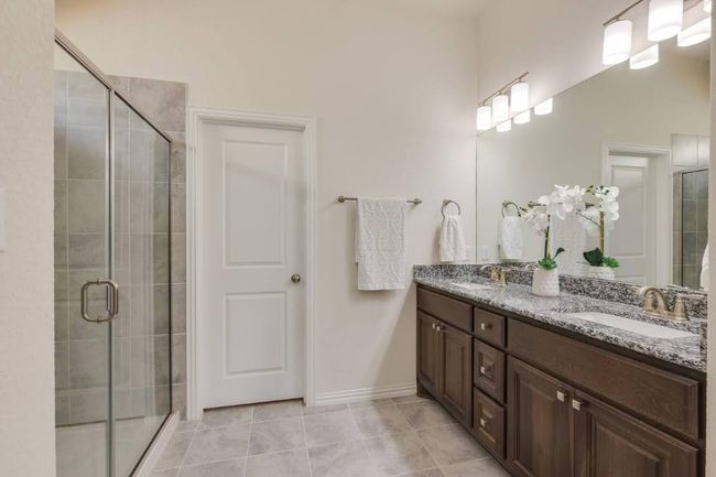 Full bathroom with double vanity, a shower stall, tile patterned flooring, and baseboards | Image 24