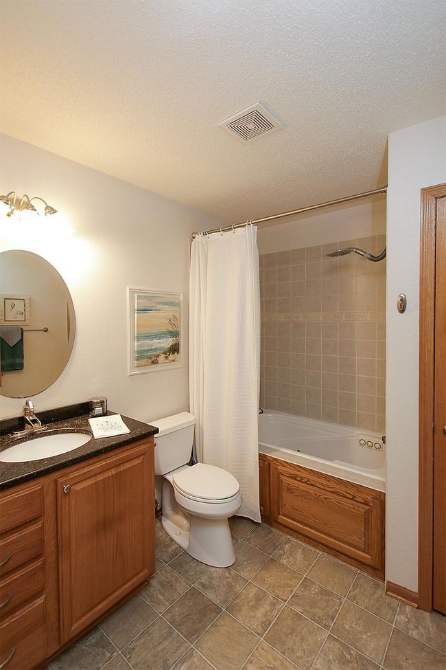 The guest bathroom features an oak vanity with a granite countertop, and a relaxing whirlpool jacuzzi tub. | Image 11