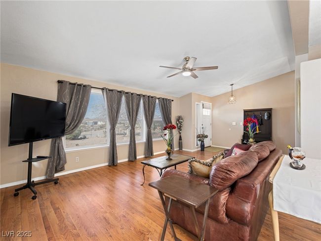 Living area featuring lofted ceiling, baseboards, light wood-type flooring, and a ceiling fan | Image 18