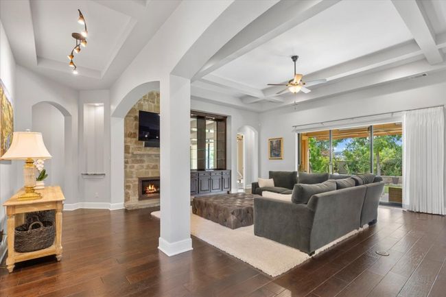 Living room featuring arched walkways, coffered ceiling, a ceiling fan, hardwood / wood-style flooring, and a fireplace | Image 5