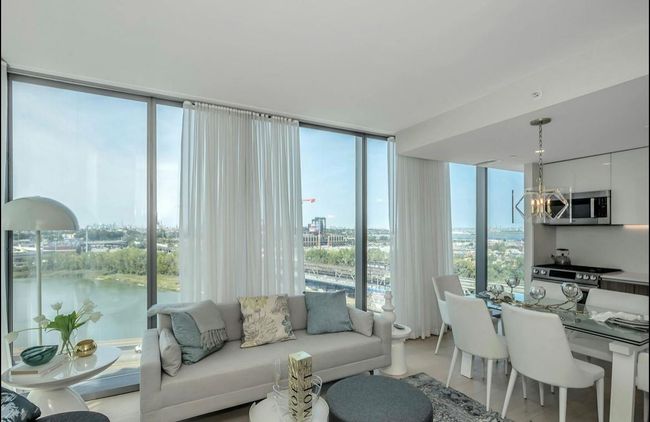 Living area featuring expansive windows, a chandelier, a view of city, and light wood finished floors | Image 5