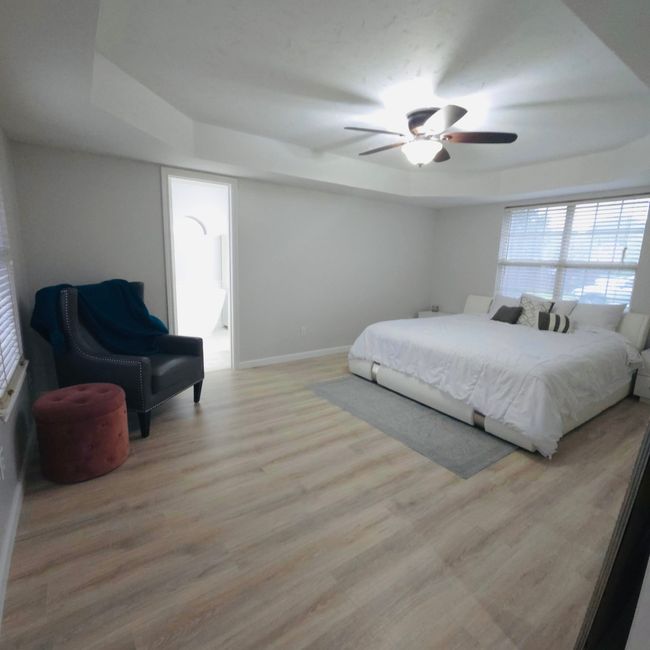 Bedroom featuring a raised ceiling, light wood-style floors, and ceiling fan | Image 15