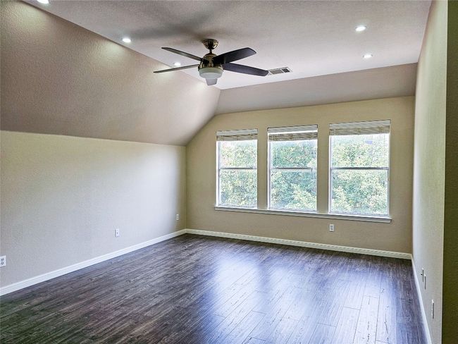 Additional living space featuring dark wood-style flooring, a ceiling fan, lofted ceiling, baseboards, and a textured ceiling | Image 21
