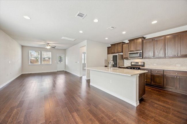 Kitchen featuring a center island with sink, tasteful backsplash, stainless steel appliances, and visible vents | Image 4