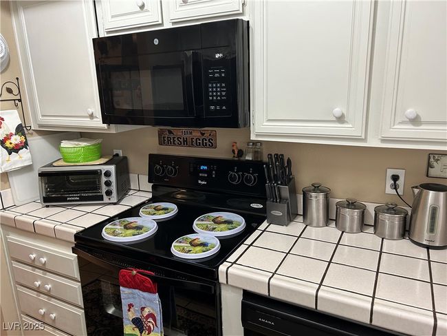 Kitchen featuring black appliances, tile counters, and white cabinetry | Image 15