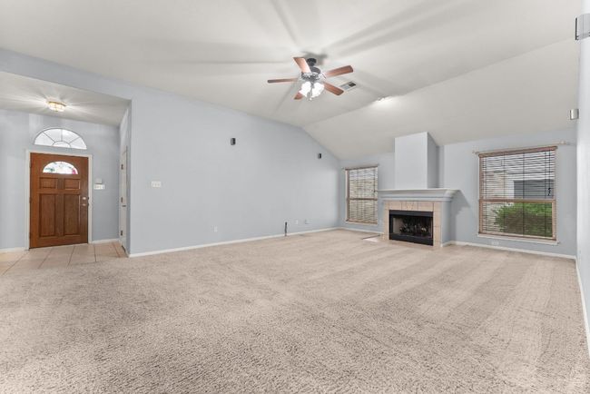 Unfurnished living room featuring light colored carpet, ceiling fan, and a healthy amount of sunlight | Image 6