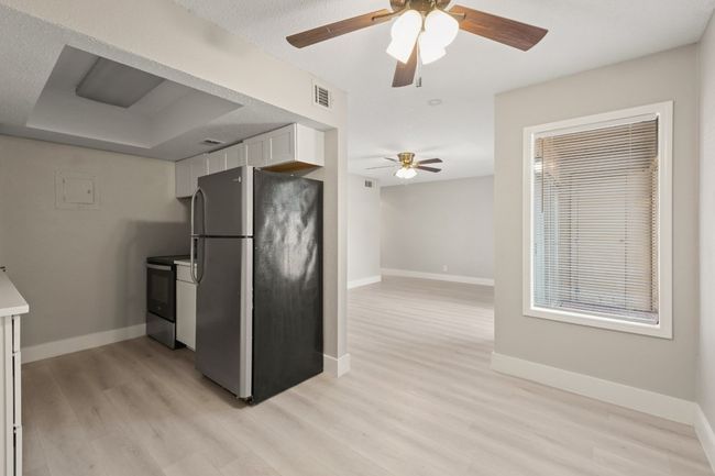 Kitchen featuring appliances with stainless steel finishes, white cabinetry, light wood-type flooring, and ceiling fan | Image 9