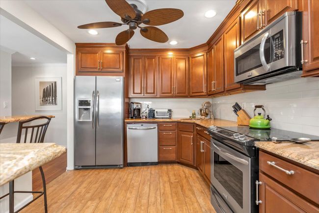 Kitchen featuring decorative backsplash, light wood-style flooring, a ceiling fan, appliances with stainless steel finishes, and a sink | Image 4