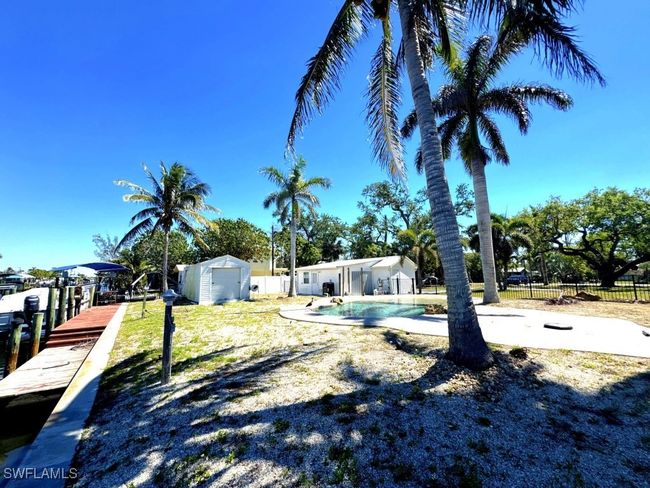 View of yard featuring a fenced in pool, a storage shed, an outdoor structure, and fence | Image 26
