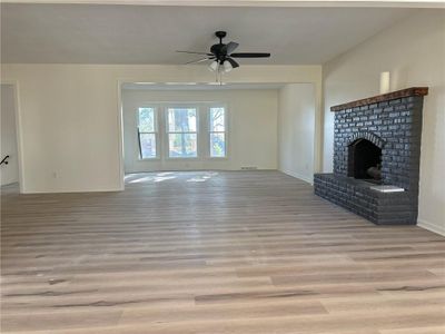 Unfurnished living room with a brick fireplace, light wood-type flooring, and ceiling fan | Image 2