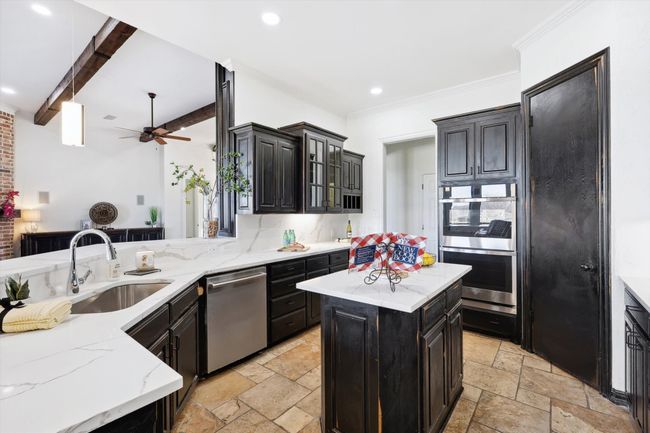 Kitchen featuring stainless steel appliances, a sink, stone tile flooring, backsplash, and ceiling fan | Image 13