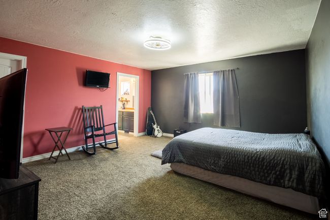 Carpeted bedroom with baseboards, a textured ceiling, and ensuite bathroom | Image 11
