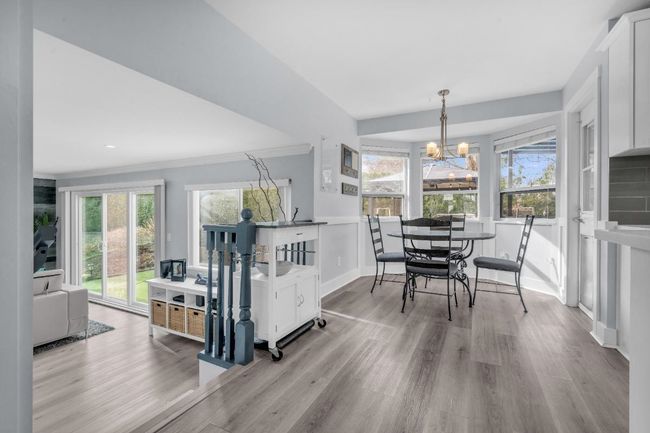 Dining space with baseboards, crown molding, an inviting chandelier, and wood finished floors | Image 12