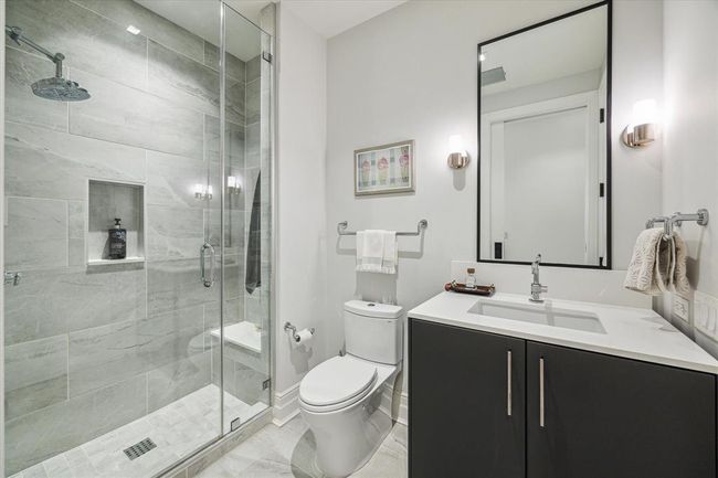 [Secondary Bath] Spacious walk in shower with bench and niche, accented with chrome hardware. Vanity elegantly designed with quartz countertop and custom cabinet | Image 32