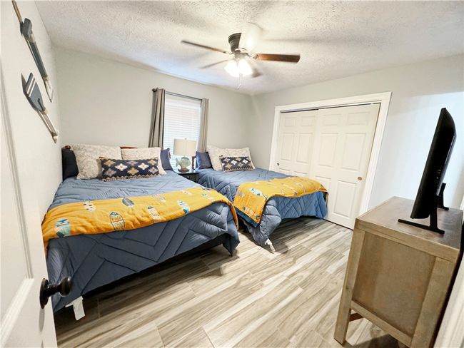 Bedroom featuring ceiling fan, a closet, a textured ceiling, and light wood-style flooring | Image 7