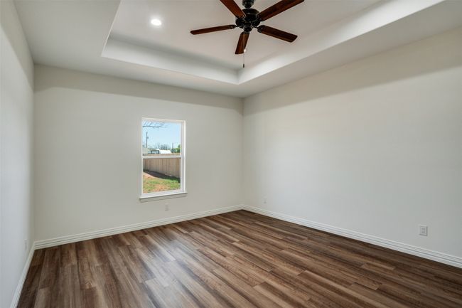 Spare room featuring dark wood finished floors, ceiling fan, baseboards, and a raised ceiling | Image 14
