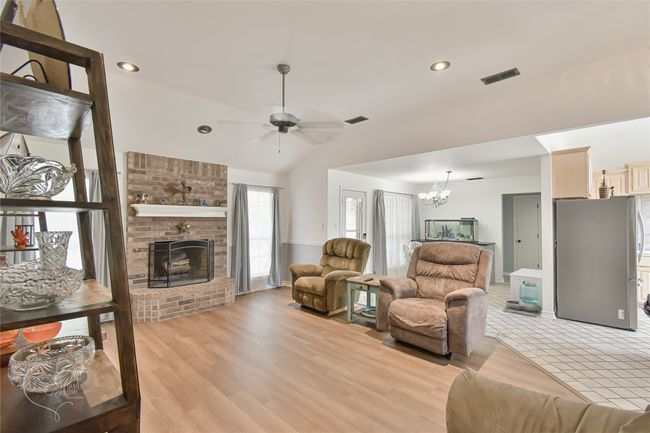 Living room with ceiling fan, a chandelier, a brick fireplace, lofted ceiling, and recessed lighting | Image 29