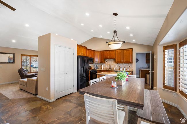 Kitchen with baseboards, tasteful backsplash, black appliances, vaulted ceiling, and brown cabinetry | Image 9