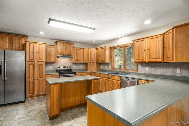 Kitchen featuring backsplash, appliances with stainless steel finishes, sink, a kitchen island, and a textured ceiling | Image 34