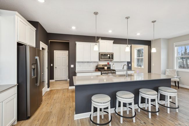 The kitchen is a showstopper, boasting a 10-foot island with solid surface countertops, all-white cabinetry, a walk-in pantry, and access to mudroom and oversized garage. | Image 8