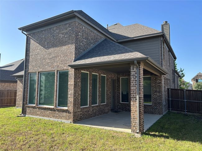 Rear view of property featuring brick siding, a patio, a chimney, and roof with shingles | Image 19