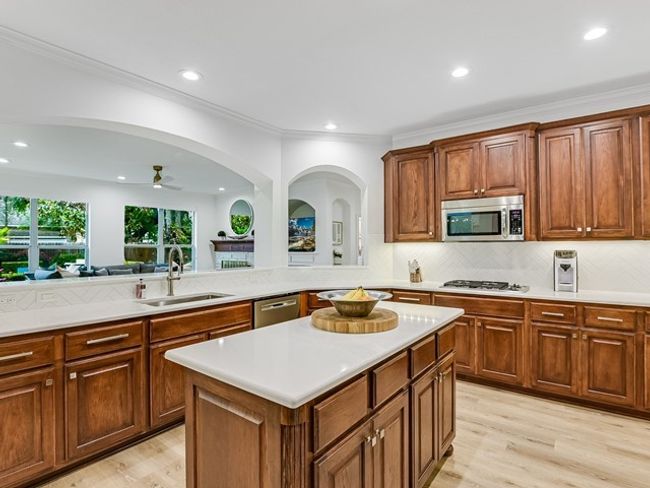 Kitchen with light countertops, a sink, a kitchen island, tasteful backsplash, and appliances with stainless steel finishes | Image 10