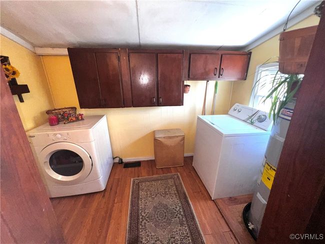 Laundry area featuring cabinets, washer and clothes dryer, hardwood / wood-style floors, and water heater | Image 22