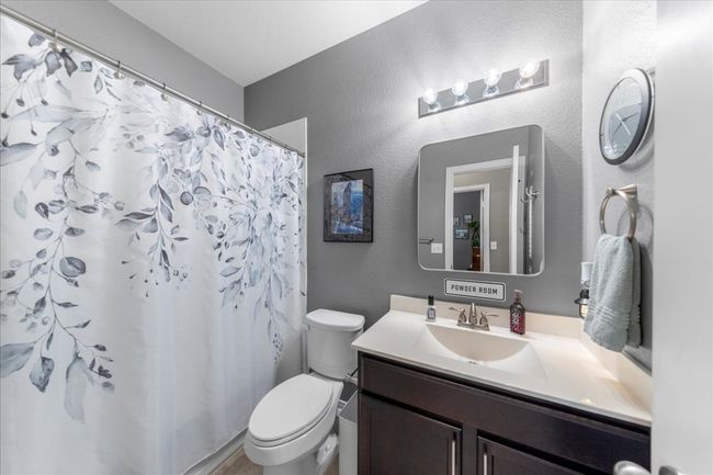 Bathroom featuring a textured wall, vanity, and curtained shower | Image 13