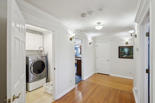 Washroom with crown molding, washer / dryer, light wood finished floors, baseboards, and cabinet space | Image 31