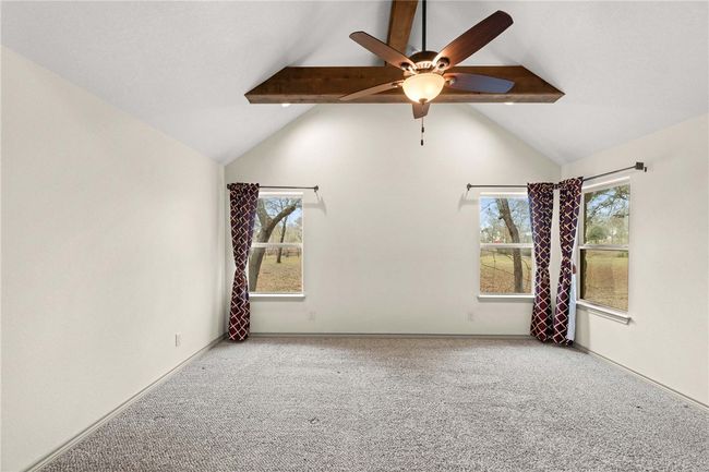 Unfurnished room featuring lofted ceiling with beams, a ceiling fan, baseboards, and carpet flooring | Image 12